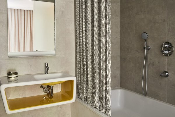 Couleurs minérales pour la salle de bains avec une touche de couleur vive comme le jaune qui ponctue la vasque avec rangement intégré.