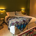 Courtepointe en patchwork et tapis d’esprit vintage pour cette chambre double de 30 m². Papier-peint, modèle Palm Jungle, chez Cole & Son.