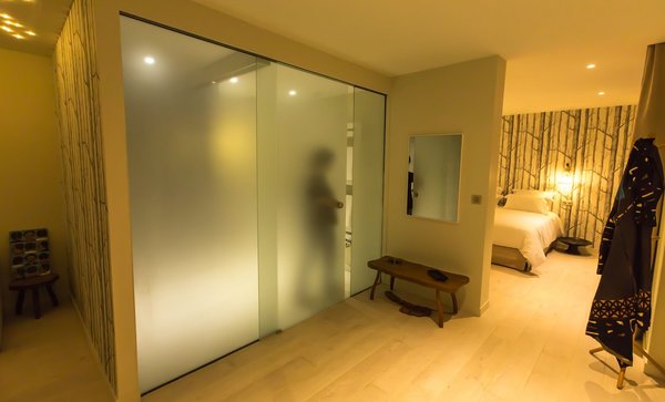 Des panneaux de verre translucide, mais qui garantissent l’intimité, cloisonnent la salle de bains.