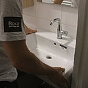 Etape 9 : La vasque est posée sur le meuble, fixée au mur par des vis et collée par le joint silicone précédemment apposé.