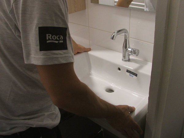 Etape 9 : La vasque est posée sur le meuble, fixée au mur par des vis et collée par le joint silicone précédemment apposé.