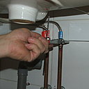 Etape 10 : Les flexibles d’alimentation fournis avec la robinetterie sont raccordés aux arrivées d’eau chaude et froide, à l’aide d’une clé à molette ou une clé plate.