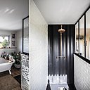 La grande salle de bains a été imaginée dans un style romantique avec une baignoire en acrylique sur pieds (Leroy Merlin) et une immense douche de style industriel recouverte de carrelage métro sur les côtés, mais qui a conservé la tôle du container pour faire office de fond de douche. Pomme de douche en cuivre et robinetterie façon robinets de puisage d’antan.