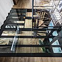 Afin d’apporter de la lumière au rez-de-chaussée, un plancher de verre composé de panneaux de verre Securit fait office de puits de lumière. Toutes les fenêtres de la maison sont en aluminium anthracite double vitrage.