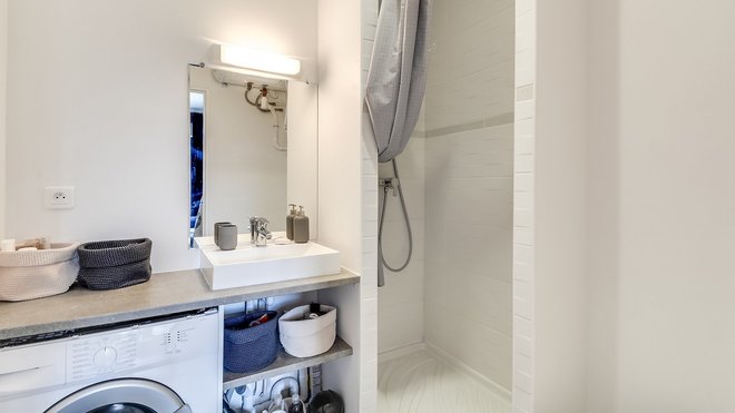 La salle de bains a été entièrement réagencée. L’ancienne baignoire qui prenait trop de place a été remplacée par une douche et un plan vasque. Dessous, un espace a été créé pour placer le lave-linge et des rangements bien pratiques.