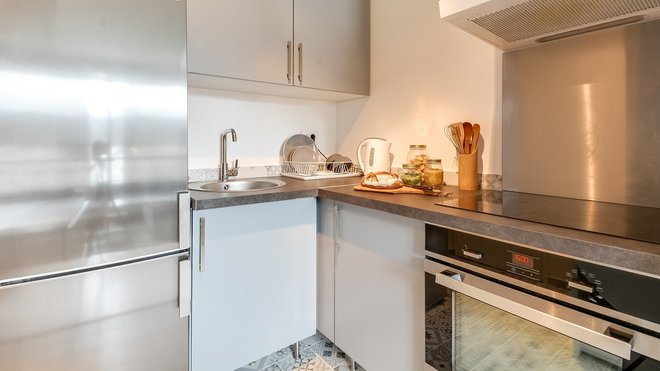 La cuisine en gris et inox a été aménagée dans l’ancienne entrée.