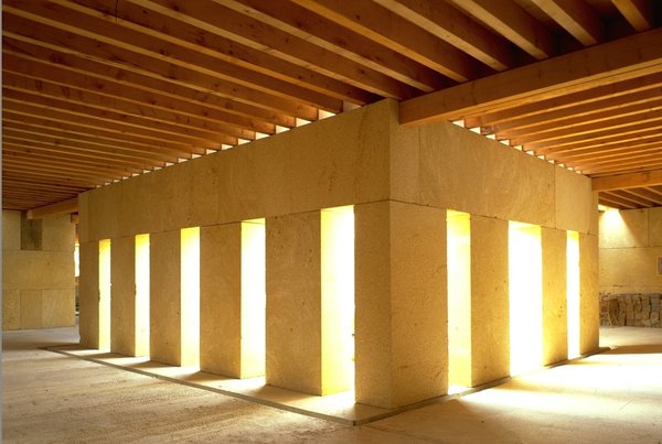 Le Chai viticole de Vauvert est un bâtiment compact et carré en pierre massive « du Pont du Gard ». Peu ouverte, son architecture réclamait aussi une grande inertie pour éviter les variations thermiques fatales à la bonne conservation des vins. Réalisation Gilles Perraudin, en 1998.