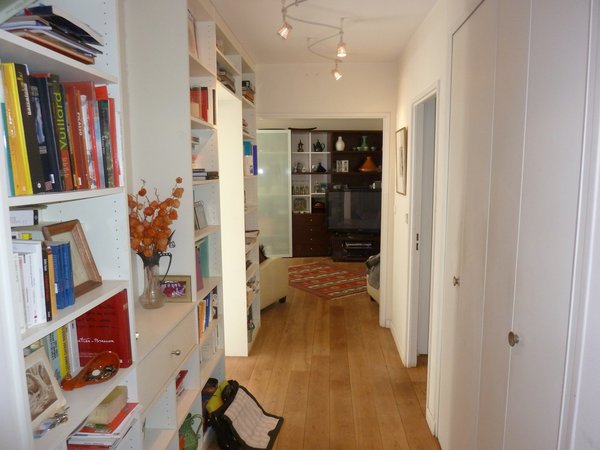 Avant les travaux : un couloir et une entrée encombrés par des rangements ouverts.