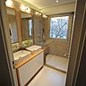 Après les travaux : un meuble intégrant deux vasques surmontées de deux miroirs cachant des rangements. Un éclairage intégré. Une douche à l’italienne, avec porte en verre, qui permet de profiter visuellement de l’espace. Le siphon est placé sous un banc en bois à proximité de la colonne de douche. Les matériaux (bois, grés cérame, béton) sont déclinés dans une harmonie de beiges très actuelle et chic.