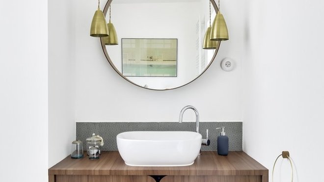 La salle de bains des parents avec meuble vasque en bois, cadre de miroir et suspensions en laiton.