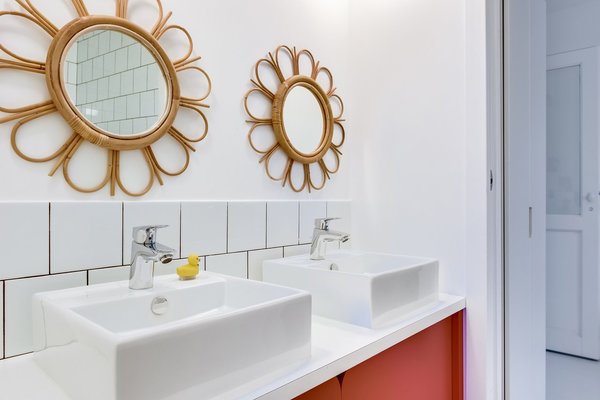 Plan avec double vasque pour la salle de bains des enfants surmonté de miroirs avec cadres en rotin.