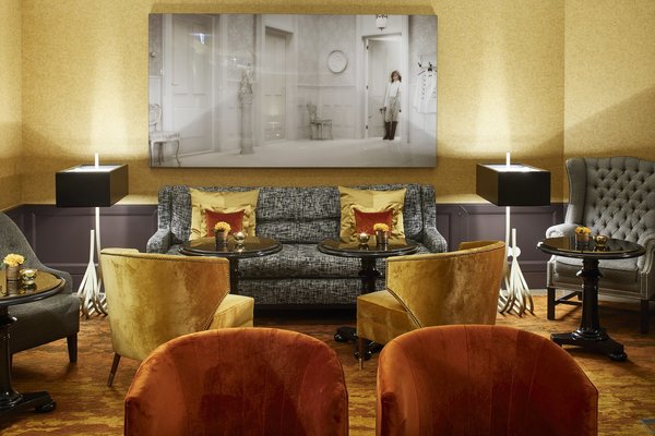 Dans l’espace du bar Lilly, les couleurs solaires répondent aux boiseries sombres et à l’onyx illuminé du bar. Au mur, une photo d’Erwin Olaf.