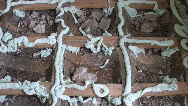 Etape 10 : Retirer les panneaux de bois aggloméré qui étaient posés à blanc, et appliquer des cordons de colle mousse polyuréthane sur l’ensemble des lambourdes ainsi que des traverses.