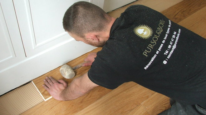 Etape 20 : Les dernières lames de parquet sont posées toujours par emboitement en les faisant légèrement glisser sous la plinthe. Le maillet en caoutchouc est utile dans ce cas de figure afin de bien positionner les lames et de les faire adhérer les unes aux autres.