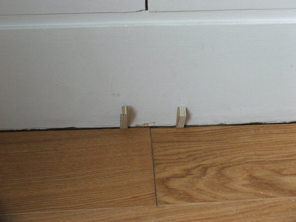 Etape 21 : Placer sur les deux à trois dernières lames de parquet, des cales en bois taillées en biseau afin de bien emboiter les dernières lames les unes aux autres.