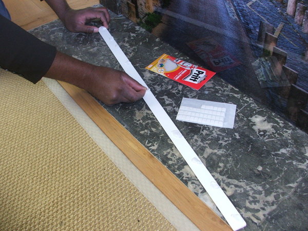 Etape 3 : afin de bien caler le visuel décoratif dans l’enfoncement du foyer de la cheminée, il est recommandé de placer une moulure en bois. Pour faciliter la tâche, le plus simple est d’utiliser de Patafix. Ensuite, placer sur le revers de la moulure de fines pastilles de Patafix, espacées de 10 cm.