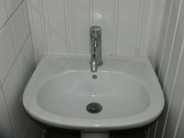 Avant le remplacement : l’ancien mitigeur de salle de bains usé et terni par le temps.