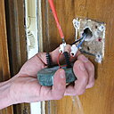 Etape 7 : relier les deux dominos du bouton de la sonnette avec les deux fils existants. Vérifier à bien serrer les vis des dominos. Puis, enfoncer l’ensemble de la sonnette dans les deux trous d’emplacement percés préalablement dans le mur.