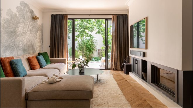 Un salon télé avec sa nouvelle cheminée encastrée contemporaine. Papier-peint Jungle Land, chez Rebel Walls.