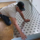 Etape1 : Dérouler la sous couche d’isolation phonique pour la mise en œuvre du revêtement de sol. Afin de respecter parfaitement les règles de pose nous utiliserons ici une sous couche avec pare-vapeur intégré de la Marque Arbiton (MultiProtec Absolute). La sous couche à base de charges minérales naturelles possède un très fort pouvoir d’isolation phonique, 21 Db et de réduction du bruit de pas dans la pièce (30%).