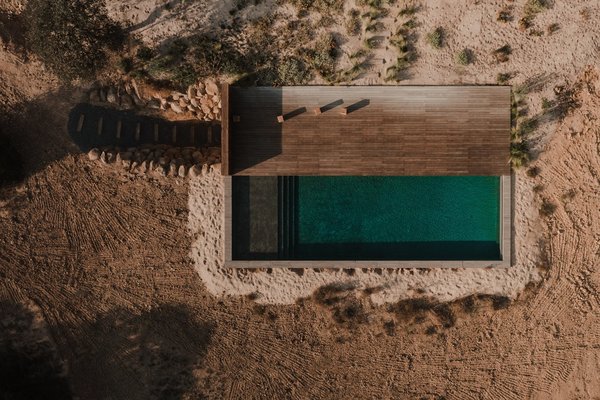Une piscine avec terrasse en bois qui fusionne avec la terre.