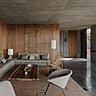 La décoration textile rappelle les couleurs du plafond en béton et les meubles déclinent un camaïeu de tons boisés.
